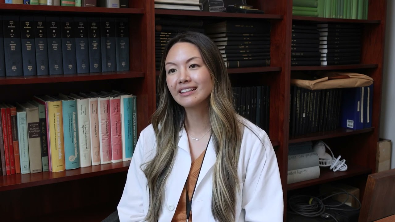 Student in Physiology sits in room full of books