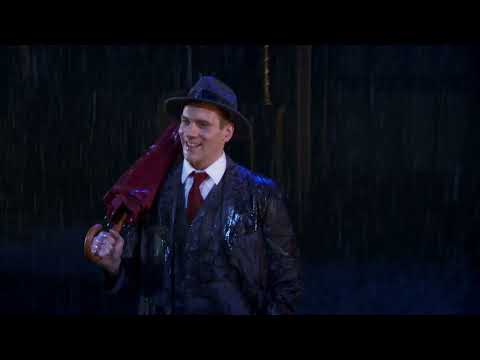 Trailer moment: star under lamppost mid-splash, celebrating the standing-ovation title number