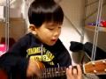 Очень маленький мальчик играет на гитаре. 