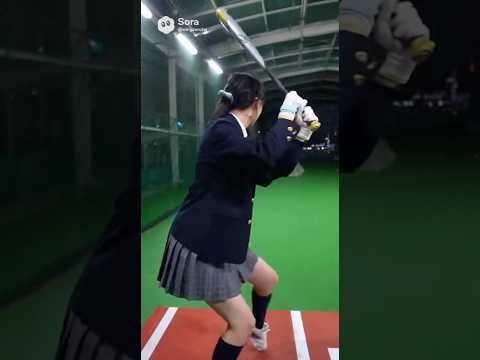 日本の女子高生がバッティングセンターで野球を打ち、カキーンと快音を響かせる。