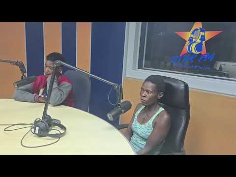 A woman speaking into a radio microphone in a studio.