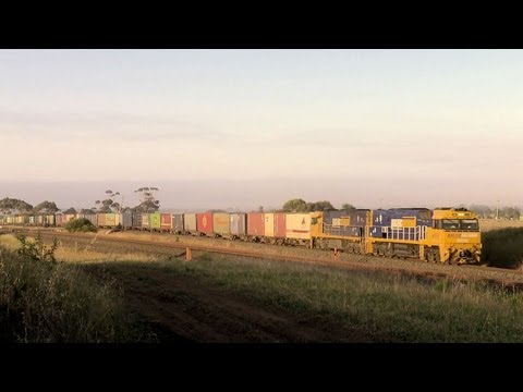 Long Freight Train & Passenger Train Speed Through a Railway Level Crossing - PoathTV