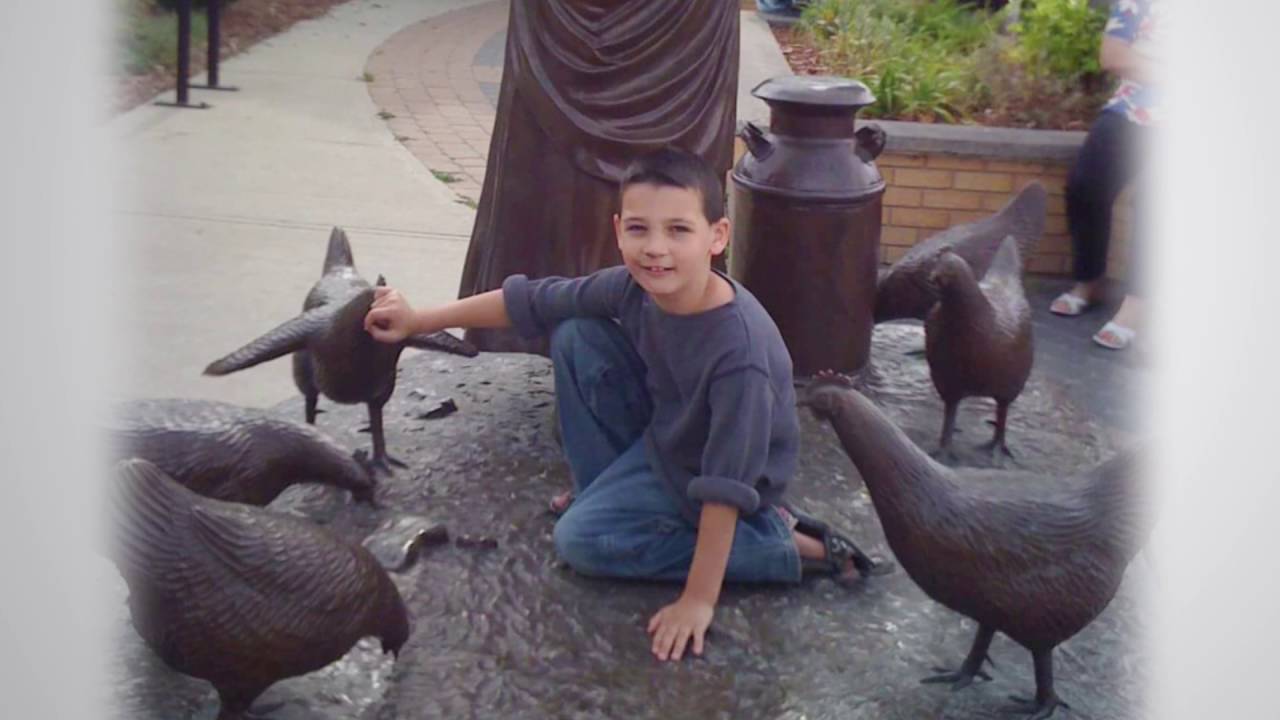 Aiden outside on a sculpture of chickens with a milk can