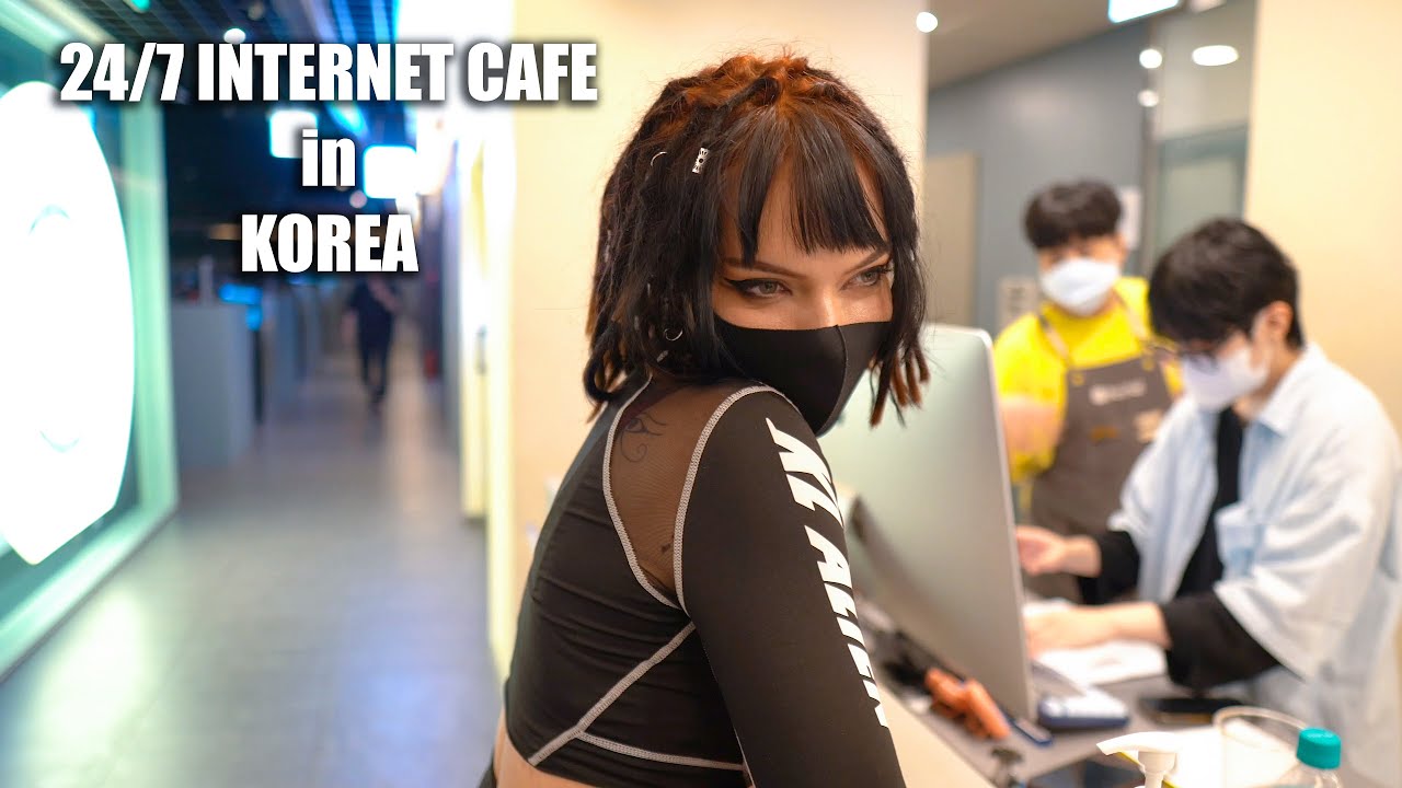 Inside a Korean PC bang gaming cafe with rows of monitors gaming chairs and players seated under colorful LED lighting in Seoul