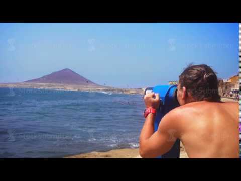 Man looking through binoculars on the coast of the blue sea