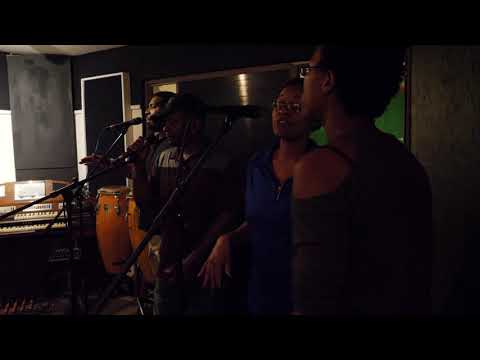 G. June performing with live musicians in an archival promotional video