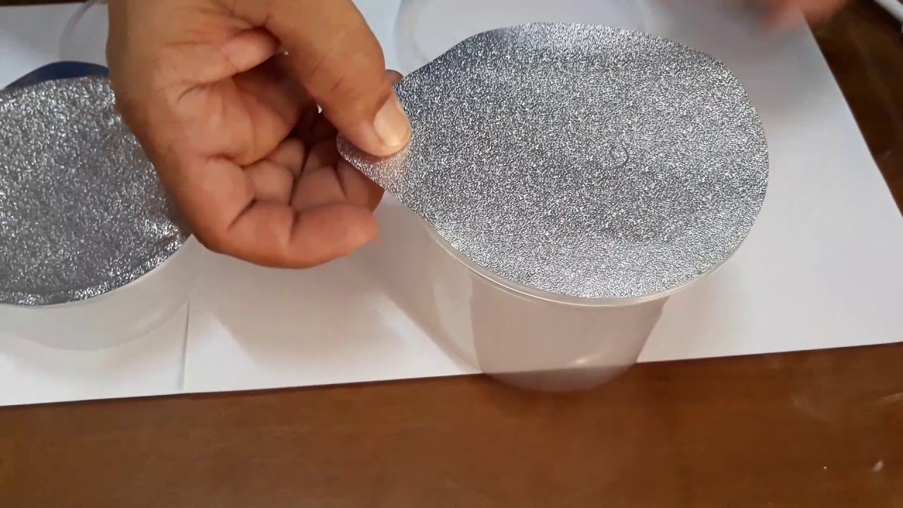 Aplicando selos de aluminio em potes plasticos.