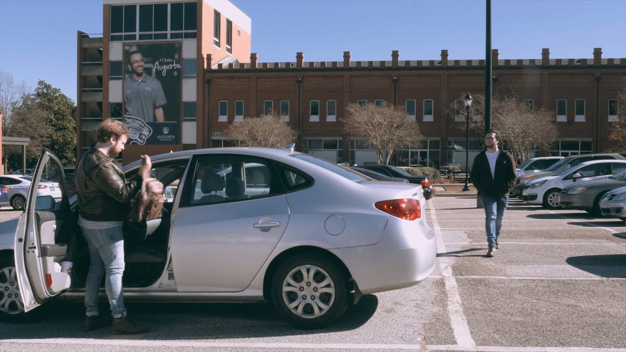 A person gets into their car as a stranger approaches