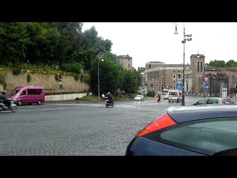 An ambulance, a bus, and five motorcycles go together at Rome