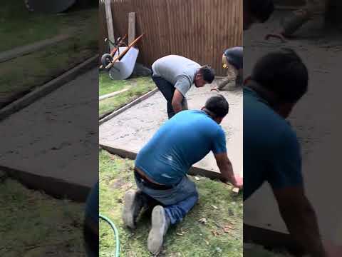 Leveling the poured concrete mixture in the platform box prior to troweling.
