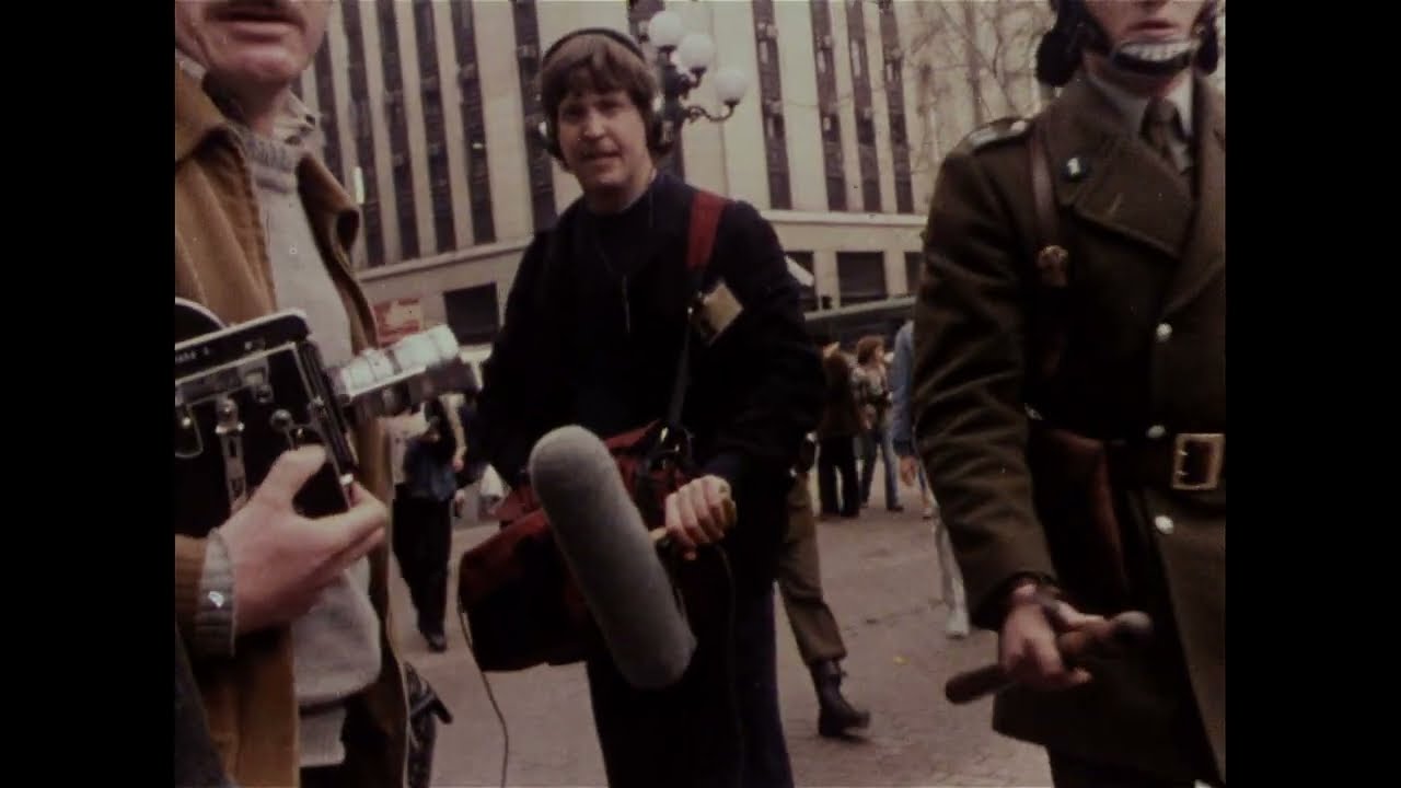 A group of filmmakers on the street carrying camera equipment.