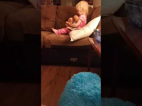 Baby girl reading her baby dolls a bedtime story