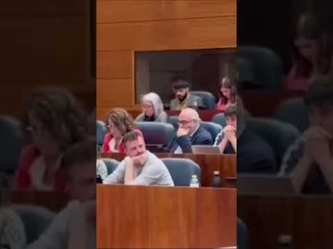 Pablo Padilla, a Más Madrid MP, pretends to fire a pistol during Ayuso's speech.