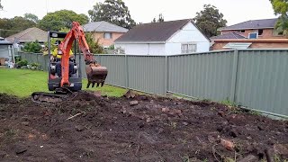 Mini Excavator excavating levelling and reshaping the yard