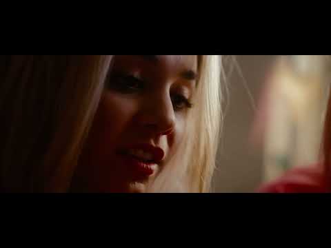 Trailer close-up: neon masks and shotguns against a dreamy pop ballad vibe