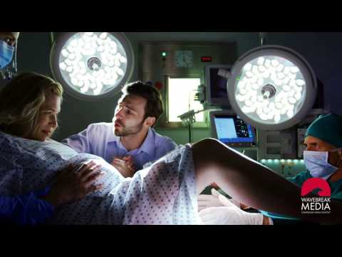 Women giving birth in hospital with husband and doctors | WaveBreak Media