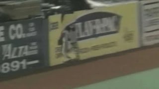 Rodney McCray crashes through the outfield fence