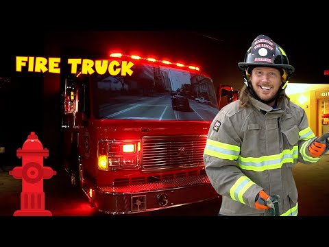 Smiling firefighter in turnout gear with a red fire truck inside a station and bold 'FIRE TRUCK' text in yellow above.