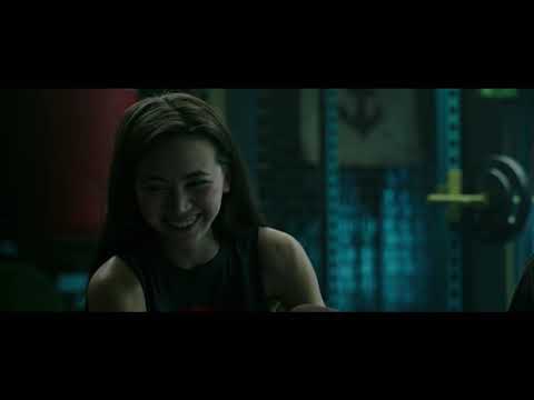 End-card trailer frame — floodlights and particulate haze as the music drops to a low, ominous hum