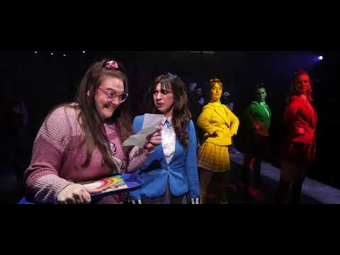Heathers: The Musical trailer still of Veronica Sawyer facing the Heathers in a school hallway