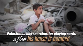 Palestinian boy searches for playing cards after his house is bombed
