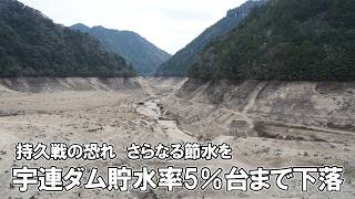常時満水位から41㍍下がっていると説明する松岡課長㊧＝新城市川合の宇連ダムで