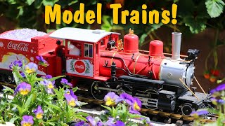 Big Model Trains Running On Tracks Around The Flower Garden