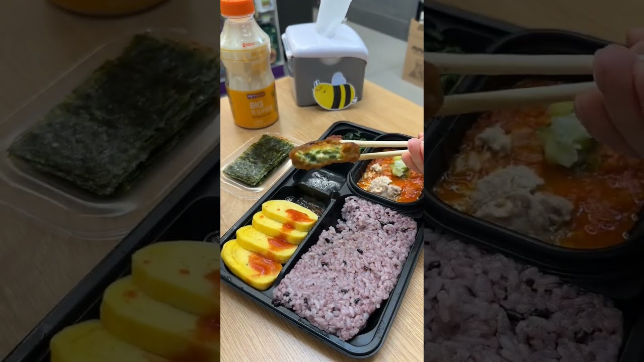 A Korean convenience store GS25 dosirak with multiple compartments containing rice bulgogi banchan kimchi and dessert arranged neatly in plastic packaging