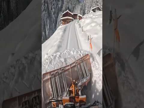 Clearing snow in the mountains with a tractor.