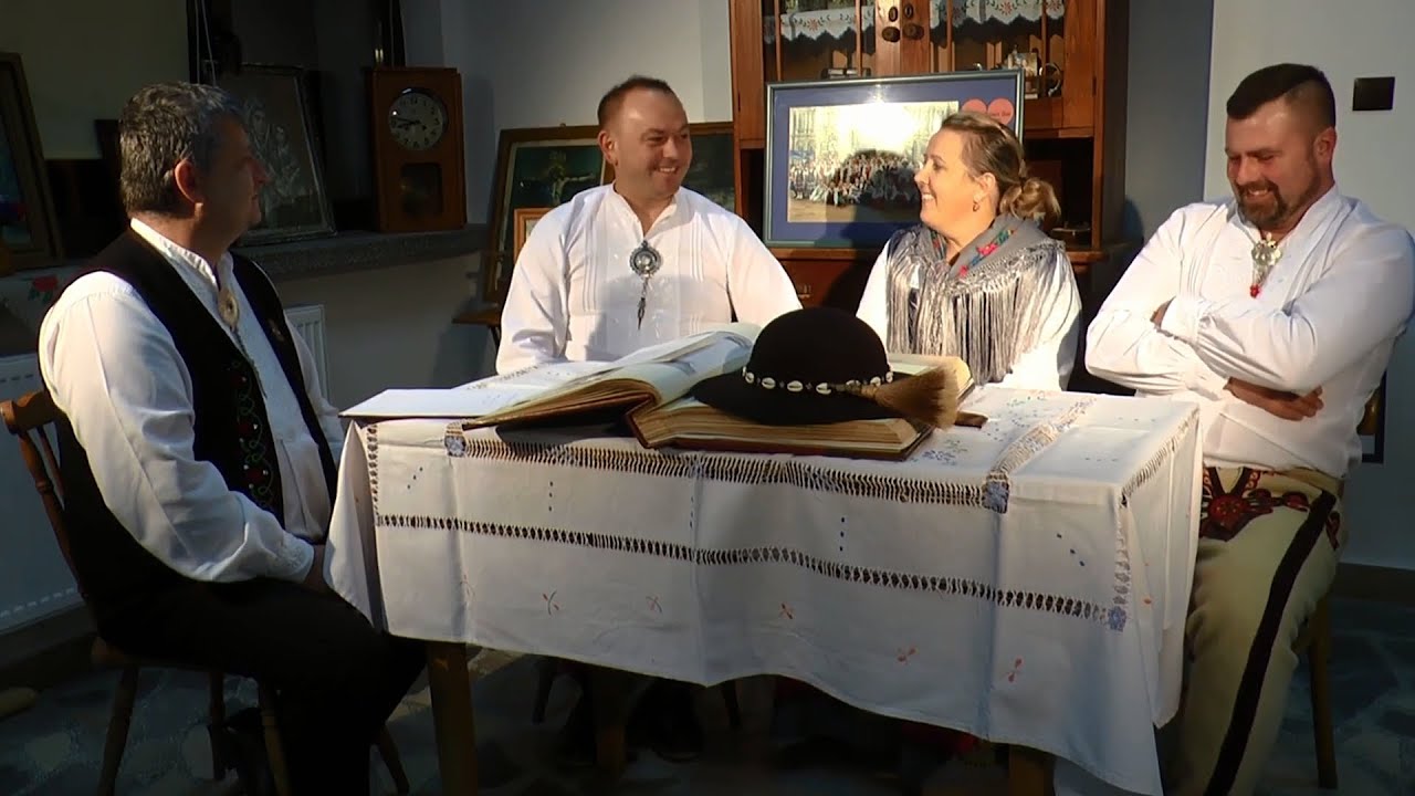 Troje mężczyzn i jedna kobieta ubranych w stroje podhalańskie siedzą przy stole