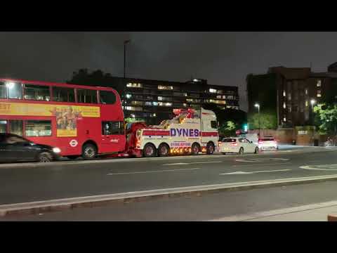 A classic red double-decker London bus broke down and a mega crane comes to take it away
