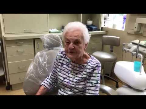 Elderly woman in striped shirt sitting in dental chair