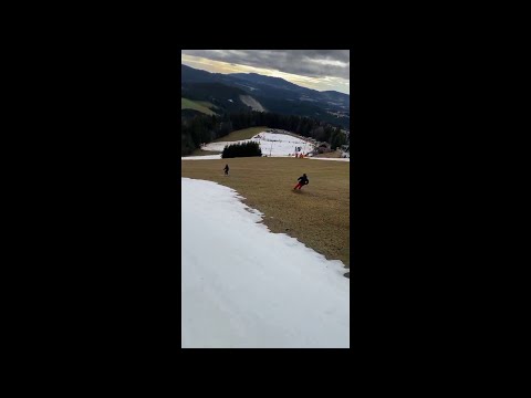 Skiers ride on grass as warm weather causes snow shortage in the Alps