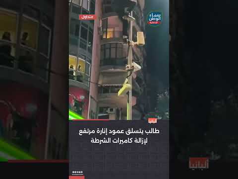 طالب يتسلق عمود إنارة مرتفع لإزالة كاميرات الشرطة