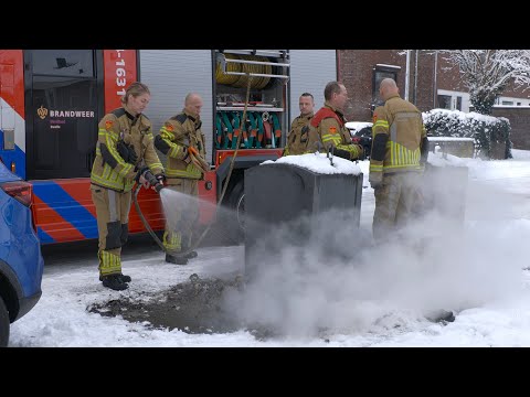 Brandweer blust brandend (vuurwerk)afval naast container op de Fonteinkruid in Zwolle