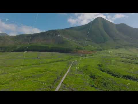 Forwards fly above green meadows and pastures on hill foot. Mountain ridge against sky. Natural