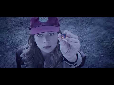 Official trailer frame: Casey’s pin lights up as Tomorrowland’s gleaming skyline surges into view