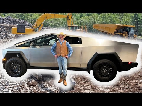 Man in cowboy hat and vest standing beside a silver Cybertruck on a rocky construction site.