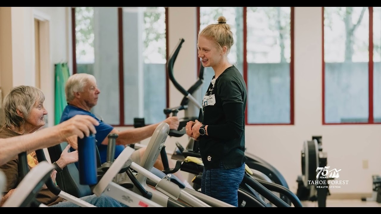 Physical therapist talking with patients while they exercise on gym equipment