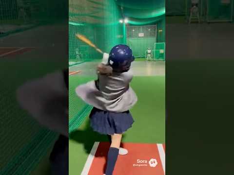日本の女子高生がバッティングセンターで野球を打ち、カキーンと快音を響かせる。
