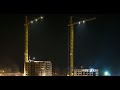 night view time lapse of silhouettes of cranes working on a construction site