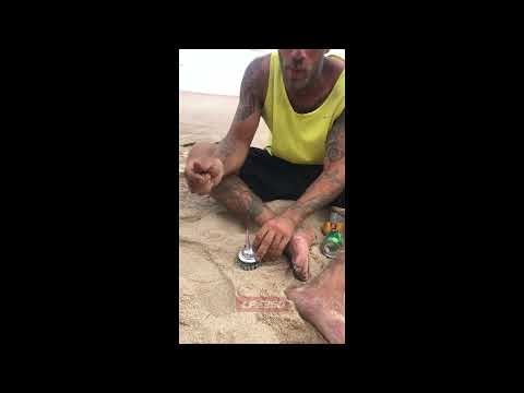 Guy on the beach makes art with beer cans