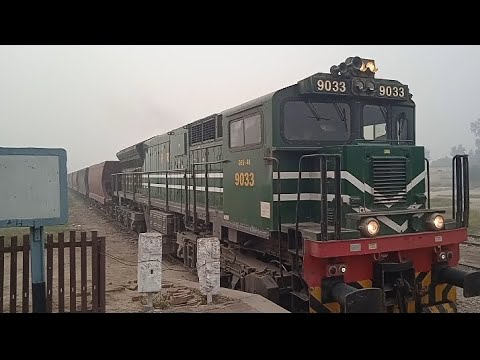 Locomotiva GEU 40 9033 conduzindo o trem de mercadorias muito longo da ferrovia do Paquistão || Entrando na estação