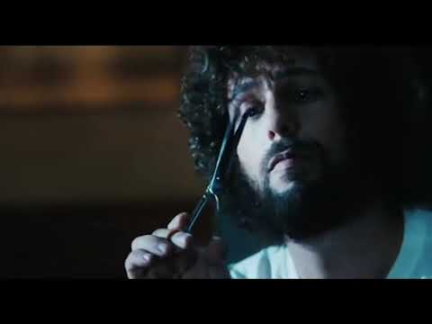 Trailer still of Zohan posing in a salon mirror with scissors and blow-dryer