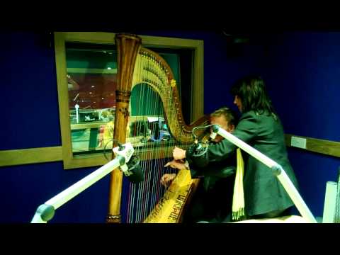 Lucinda Belle teaching Nigel Williams how to play the harp