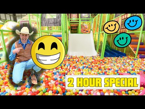 Man in a cowboy outfit sits by a giant smiling emoji in a colorful ball pit, with a playground slide and '2 HOUR SPECIAL' banner above.