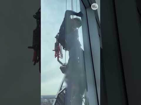 Watch crews scale high-rise to free workers stuck on titled platform
