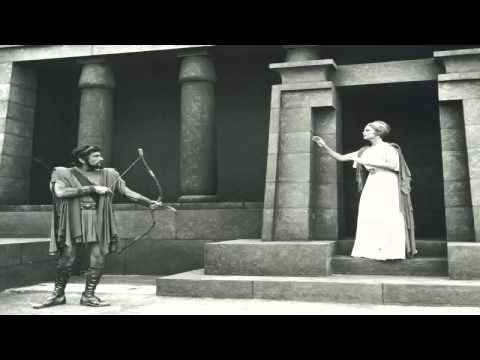 Eυριπίδης [Euripides], Ἑλένη (412 π.Χ.), παράσταση στο Αρχαίο Θέατρο της Επιδαύρου, 1977, σε σκηνοθεσία Αλέξη Σολομού, μετάφραση Τάσου Ρούσσου, μουσική Ιάννη Ξενάκη [Iannis Xenakis], σκηνογραφική επιμέλεια Κλεόβουλου Κλώνη και κοστούμια Αλέκου Φασιανού. Στους κεντρικούς ρόλους η Άννα Συνοδινού (Ελένη), ο Βασίλης Κανάκης (Μενέλαος), η Κάκια Παναγιώτου (Θεονόη) και ο Γκίκας Μπινιάρης (Θεοκλύμενος), με τους Παντελή Ζερβό ως Έλληνα Αγγελιαφόρο και Στέλιο Βόκοβιτς ως Αιγύπτιο Αγγελιαφόρο. Στην ευριπίδεια τραγικοκωμωδία οι δύο άγγελοι μεταφέρουν διαδοχικά την είδηση της εξαπάτησης του Θεοκλύμενου και τη διαφυγή των συζύγων, λειτουργώντας ως δραματουργικοί άξονες της δράσης που εκτυλίσσεται εκτός του οπτικού πεδίου της σκηνής.