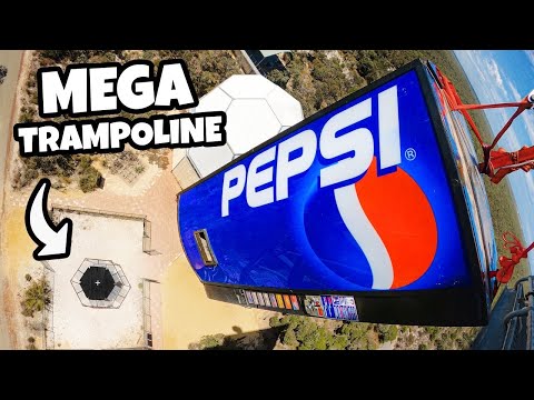 Aerial view of a large blue Pepsi sign on a tall amusement ride with bold 'MEGA TRAMPOLINE' text overlay.