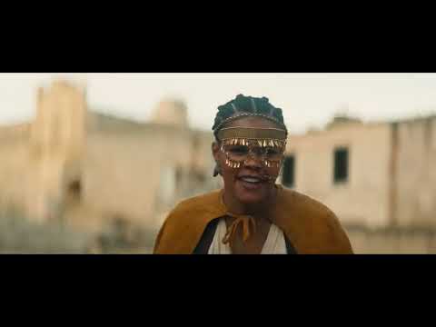 Trailer shot of Clarence racing a chariot with a defiant grin as dust and brass flare